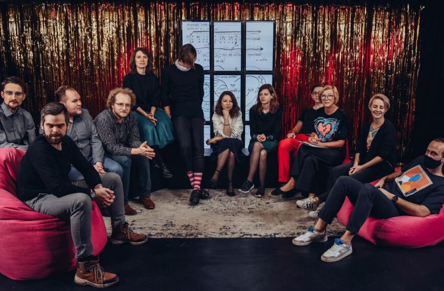 Na scenie siedzi grupa młodych ludzi, czyli zespół Spółdzielnia Muzyczna Contemporary Ensemble