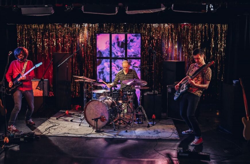 Trzech mężczyzn z zespołu Cineman gra koncert na scenie