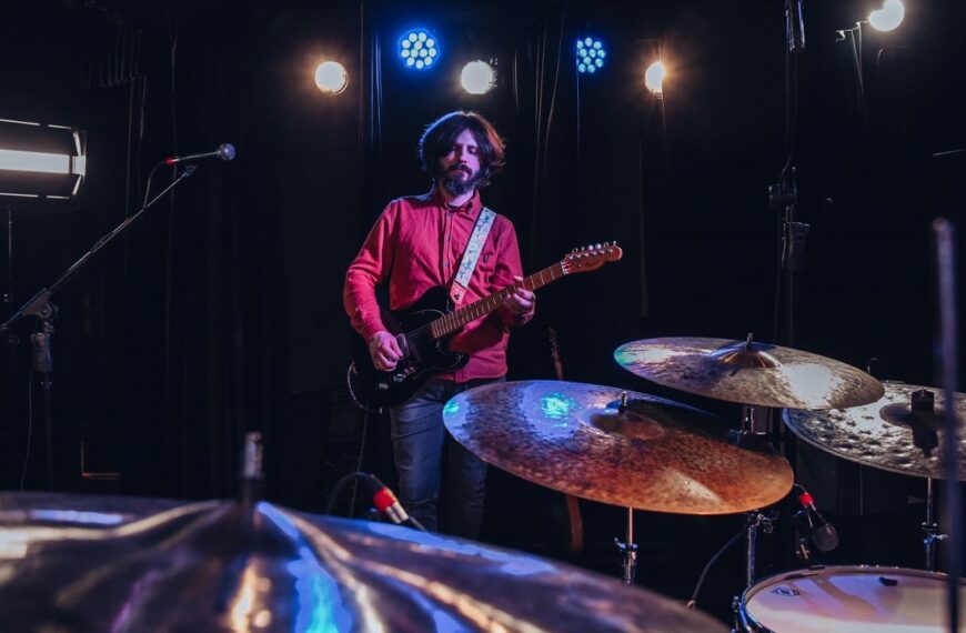 Na pierwszym planie talerze perkusyjne, za nimi stoi gitarzysta zespołu Cinemon