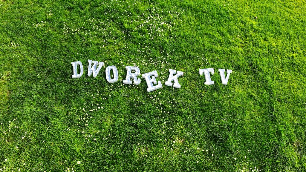 Biały napis dworek tv na trawie