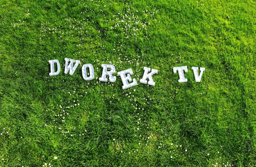 Biały napis dworek tv na trawie