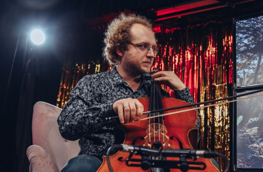 Jakub Gucik siedząc gra na wiolonczeli