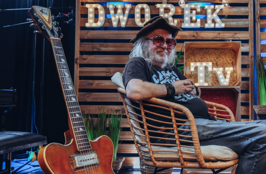 Antoni Krupa w kapeluszu i okularach siedzi na wiklinowym fotelu